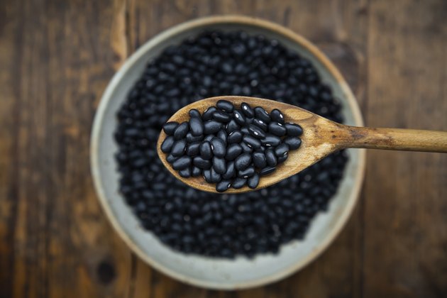 Overhead view of spoon and bowl of black bean on wooden table