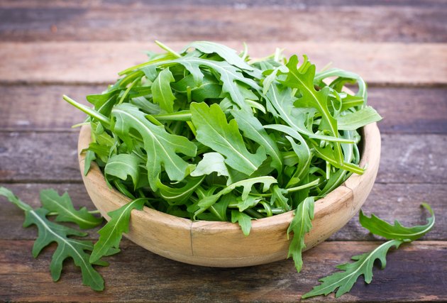 Fresh arugula salad in wooden bowl