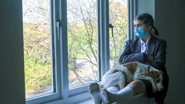 Schoolgirl with face mask looking out the window