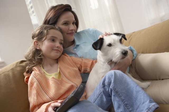 Mother with daughter (8-10) relaxing on sofa with dog
