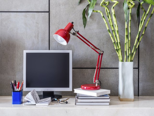 Modern office desk with computer, lamp and vase of flowers