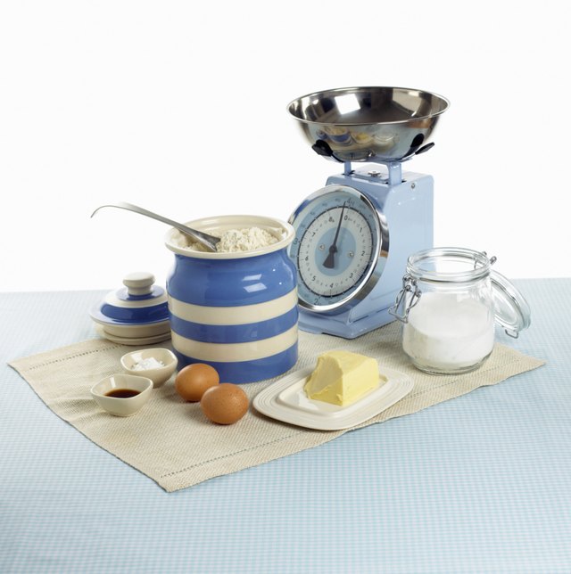 Jars of flour, sugar, pat of butter, eggs and set of scales