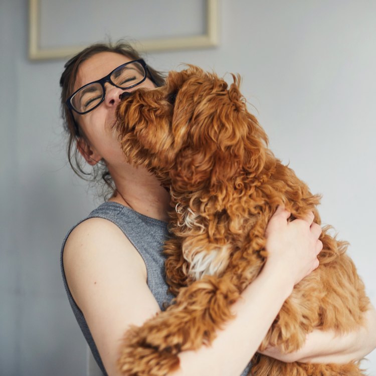 Image of a woman getting a kiss from her puppy; image credit: Sally Anscombe/Getty Images